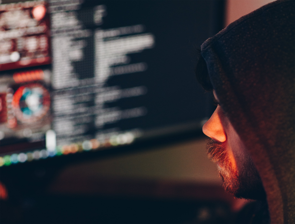 Person in a hoodie working at a computer in the dark (hacker?)